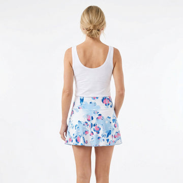 Woman wearing a white tank top and floral skirt on a white background
