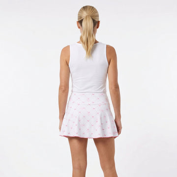 Person wearing a white sleeveless top and pink skirt with white polka dots on a white background