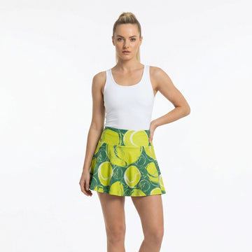Woman wearing a white tank top and green tennis skirt with lemon pattern on a white background
