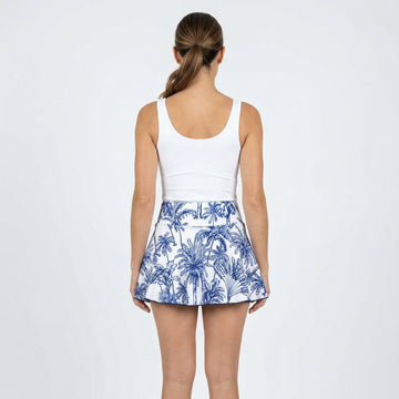 Person wearing a white tank top and blue and white patterned skirt on a white background