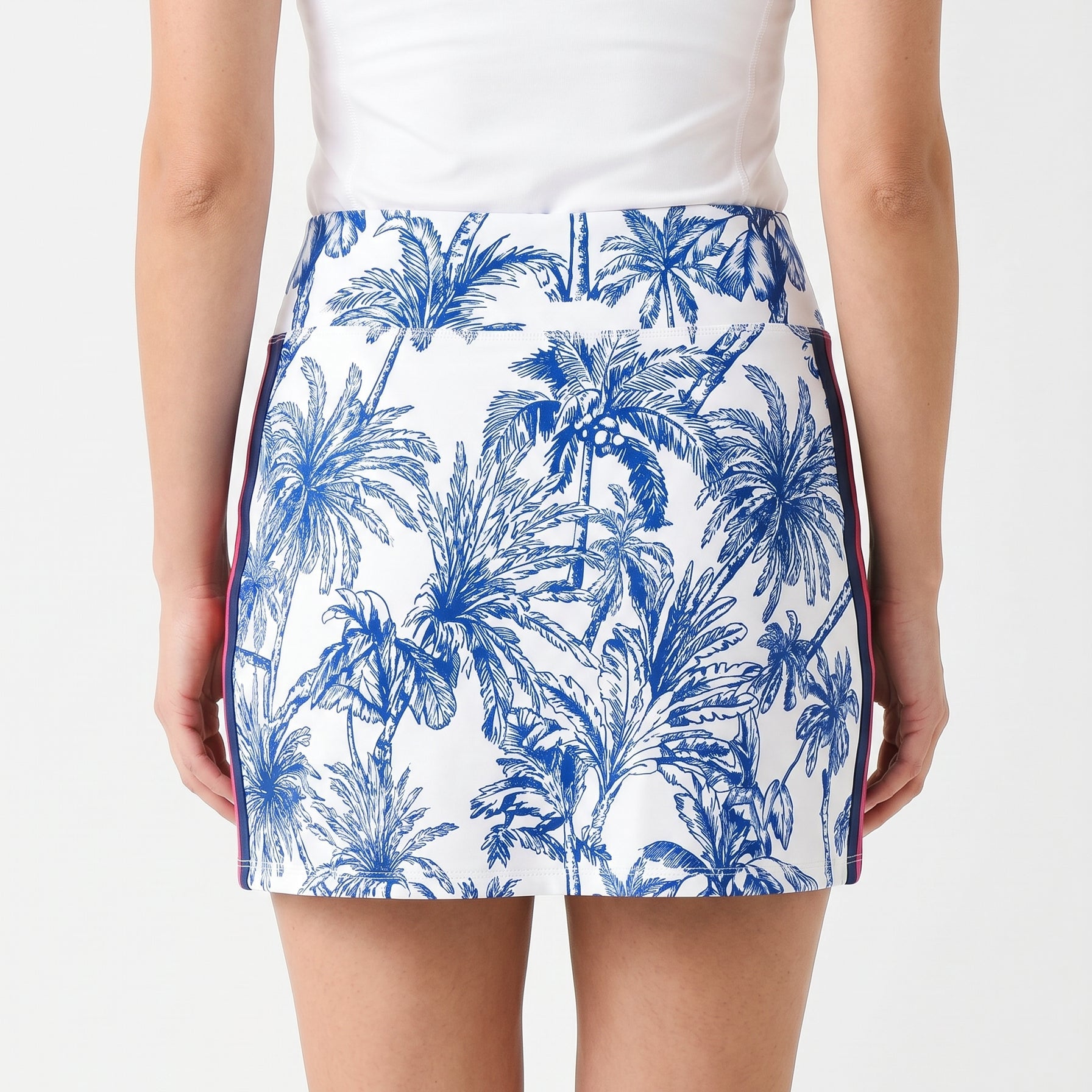 Person wearing a white top and blue palm tree patterned skirt on a white background