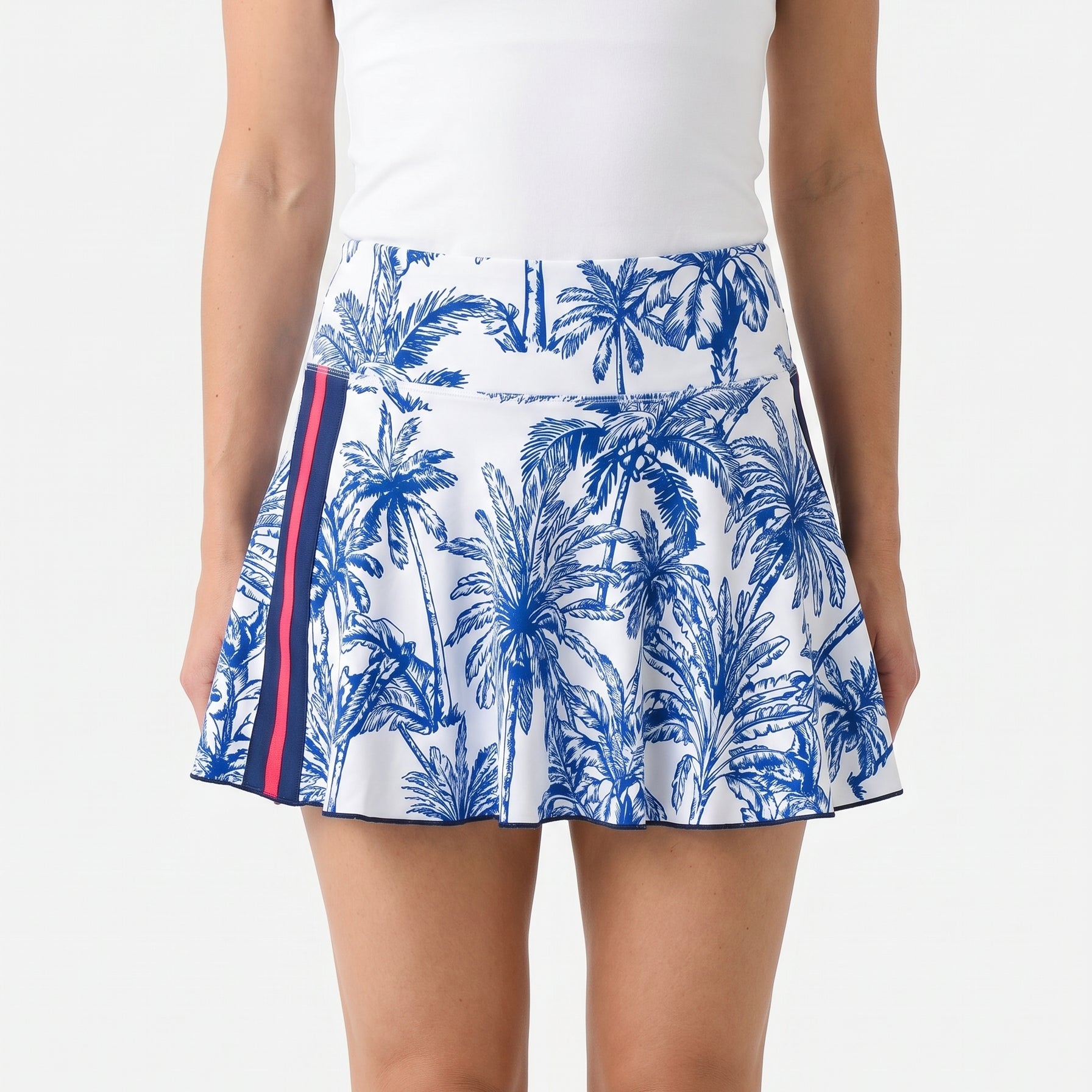 Woman wearing a white tank top and blue palm tree patterned skirt on a white background
