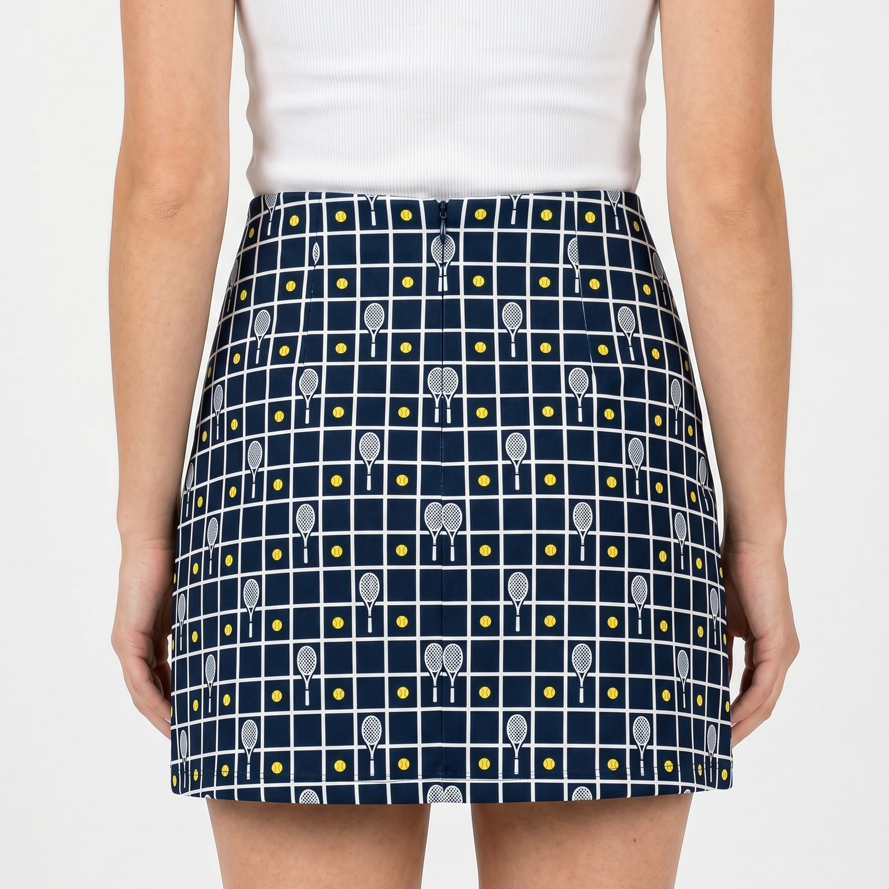 Person wearing a navy blue skirt with tennis racket pattern on a white background