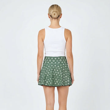Person wearing a white top and green patterned skirt on a white background