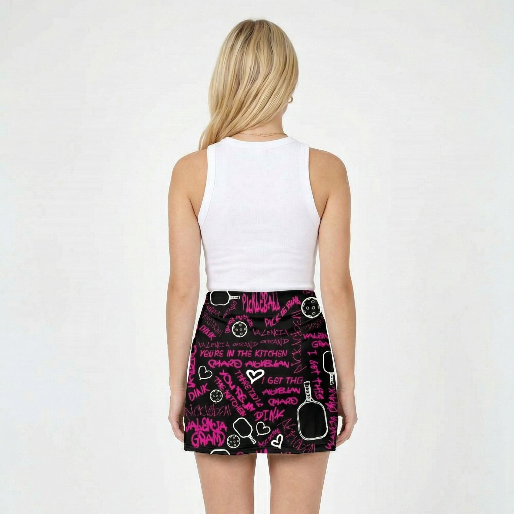 Person wearing a white tank top and black shorts with pink designs on a white background