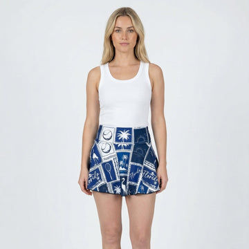 Woman wearing a white tank top and blue patterned skirt on a white background